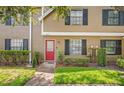 Townhouse with a bright red door, dark shutters, and well-maintained landscaping at 16504 Lake Brigadoon Cir, Tampa, FL 33618