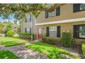 Charming townhouse with a bright red door, dark shutters, and well-maintained landscaping at 16504 Lake Brigadoon Cir, Tampa, FL 33618