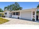 Well-maintained single-story home featuring a garage, decorative shutters, potted plants, and paved driveway at 2004 Yale Ave, Dunedin, FL 34698