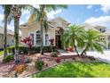 Attractive home showcasing lush landscaping with mature palm trees and colorful flowerbeds at 3300 Stonegate Falls Dr, Land O Lakes, FL 34638