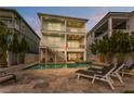 Gorgeous two-story home featuring a private backyard pool and spa with elegant stone patio at dusk at 371 12Th Ave, Indian Rocks Beach, FL 33785