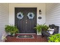 Inviting double front doors adorned with wreaths, complemented by a brick porch, bench and lush ferns at 805 Bannockburn Ave, Temple Terrace, FL 33617