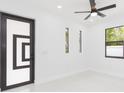 Bright bedroom featuring modern door, neutral walls, and elegant ceiling fan at 907 E Okaloosa Ave, Tampa, FL 33604