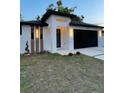 Contemporary home featuring a modern design, clean lines, a black garage door and manicured lawn at 907 E Okaloosa Ave, Tampa, FL 33604