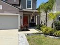 Two-story home featuring manicured garden, front lawn and front porch seating at 9616 Lemon Drop Loop, Sun City Center, FL 33573