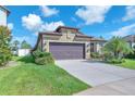 Charming single Gathering home featuring a two-car garage, landscaping, and a well-manicured lawn under a blue sky at 11606 Kilkenny Coral Dr, Riverview, FL 33579