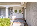 Inviting entryway with double doors adorned with wreaths, potted flowers, and brick accents at 12303 Fieldstone Ln, Hudson, FL 34667