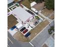 Aerial view of a one story pink house with grey roof, fenced in backyard and multiple cars parked in driveway at 12425 Ridge Rd, Largo, FL 33778