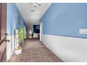 Inviting hallway with tile flooring, wainscoting, and soft blue painted walls at 14233 Edinburgh Moor Dr, Wimauma, FL 33598