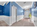Bright hallway featuring a laundry room entrance, tiled floors, and neutral carpet at 14233 Edinburgh Moor Dr, Wimauma, FL 33598