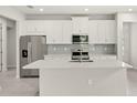 Modern kitchen features stainless steel appliances, a large island, and sleek white cabinetry at 20417 Symphony Pl, Venice, FL 34293