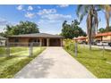 View of a charming home with fenced yard, mature trees, long driveway, and exterior architectural details at 2701 W Osborne Ave, Tampa, FL 33614