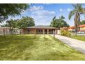 Home exterior with a fenced yard, mature trees, ample lawn space, and an extended concrete driveway at 2701 W Osborne Ave, Tampa, FL 33614