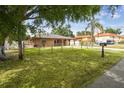 Exterior shot of a fenced single-story home featuring a large grassy yard, mature trees and an extended driveway at 2701 W Osborne Ave, Tampa, FL 33614