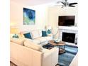 Cozy living room with a fireplace, white couch, blue rug, and ceiling fan at 323 Rex Pl # G, Madeira Beach, FL 33708