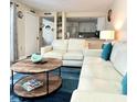 Bright living room with white couches, blue pillows, and a view into the kitchen at 323 Rex Pl # G, Madeira Beach, FL 33708