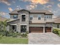 Stately two-story home showcasing stone accents, a three-car garage, and lush landscaping at 11222 Hawks Fern Dr, Riverview, FL 33569