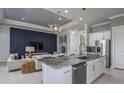 A modern open-concept kitchen boasts a spacious island, stainless steel appliances, and stylish pendant lighting at 11443 Shoreline Trl, Parrish, FL 34219