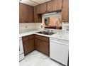 Kitchen featuring wood cabinets, white appliances, and marble-look countertops at 19029 Us Highway 19 N # 2-23, Clearwater, FL 33764
