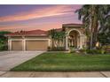 Charming exterior of home with tile roof, arched entry, and lush landscaping at sunset at 19107 Avenue Bayonnes, Lutz, FL 33558