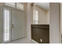 Bright foyer with white tile flooring, half wall, transom window, and white front door creating a welcoming entryway at 2220 Elizabeth Way, Dunedin, FL 34698