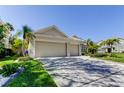 A two-car garage boasts an expansive driveway and lush landscaping, nestled in a vibrant neighborhood at 2220 Elizabeth Way, Dunedin, FL 34698