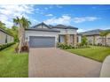 Charming single-story home with well-manicured lawn, stone accents, tile roof, and paver driveway at 4831 Rosatti Rd, Wesley Chapel, FL 33543