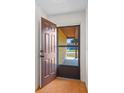 The open front door reveals tiled flooring, a screen door, and the tan stucco walls and entryway at 6109 16Th St, Zephyrhills, FL 33542
