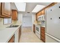 Well-lit kitchen with white appliances, wooden cabinets, and a double sink for convenience at 11762 82Nd Ter, Seminole, FL 33772