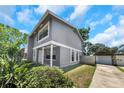 Two-story home with gray exterior, white trim, and lush landscaping in the front yard at 2048 Los Lomas Dr, Clearwater, FL 33763