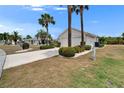 Exterior view showing home with a two-car garage, complemented by manicured landscaping and lush palm trees at 2258 Preservation Green Ct, Sun City Center, FL 33573