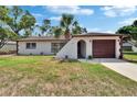 A cozy home boasting a well-kept lawn, complemented by a curved entrance and a dark-toned garage door at 3344 Blythe Ave, Spring Hill, FL 34609