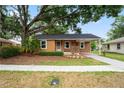 Single-story home with a covered porch, mature trees, and attached carport offering convenient parking at 5042 8Th St, Zephyrhills, FL 33542