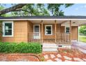 Close-up of the covered front porch with wooden railing, steps, and meticulous landscaping details at 5042 8Th St, Zephyrhills, FL 33542