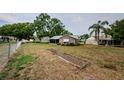 An open backyard shows the back of the house with a screened in porch and a garden at 7763 Jenner Ave, New Port Richey, FL 34655