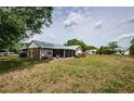 The backyard has a screened patio and is covered with dry grass and a large tree providing ample shade at 7763 Jenner Ave, New Port Richey, FL 34655
