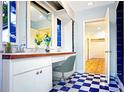 Bright bathroom with double sinks, vanity seating, and blue and white checkerboard flooring at 1111 Briarwood Rd, Brandon, FL 33511