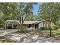 Charming ranch-style home with stone details, a long driveway, and an attached two-car garage surrounded by mature trees at 1221 Candlelight Blvd, Brooksville, FL 34601