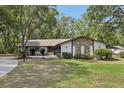 Charming ranch-style home featuring a stone facade and a lush, green front lawn surrounded by mature trees at 1221 Candlelight Blvd, Brooksville, FL 34601