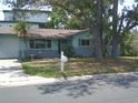 Charming one-story home with a well-maintained front yard, mature trees, and a paved driveway leading to the garage at 212 Driftwood Pl, Palm Harbor, FL 34683