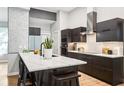 Modern kitchen featuring sleek dark cabinetry, stainless steel appliances, and a stylish waterfall island with seating at 2222 Longmore Cir, Valrico, FL 33596