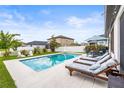 Relaxing pool area with lounge chairs, and green grass in a well maintained backyard at 34266 Radley Way, Wesley Chapel, FL 33545