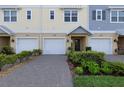 A close up exterior view of a townhome with a single car garage, brick paver driveway and manicured landscaping at 4139 Rocky Shores Dr, Tampa, FL 33634