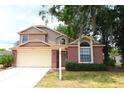Charming two-story home features a brick facade and a two-car garage with lush front lawn at 4214 Longfellow Dr, Plant City, FL 33566