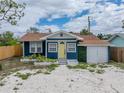 Charming single-story home featuring a blue exterior, yellow door, and a gravel driveway at 4727 17Th S Ave, St Petersburg, FL 33711