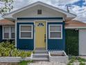 Close up of a blue home featuring a bright yellow door with a decorative window and white trim at 4727 17Th S Ave, St Petersburg, FL 33711