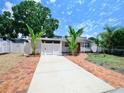 Charming one-story home with a red door, well-manicured lawn, tropical landscaping, and driveway at 4735 W Oklahoma Ave, Tampa, FL 33616