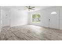 Sunlit living room featuring wood-look tile flooring and a welcoming front door at 6620 Del Prado Ter, New Port Richey, FL 34652