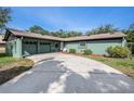 Inviting single-story home featuring a long driveway, lush lawn, and tasteful landscaping with a unique dark green exterior at 8517 Woodwick Ct, Tampa, FL 33615