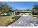 Inviting single-story home featuring a long driveway, lush lawn, and tasteful landscaping with a unique dark green exterior at 8517 Woodwick Ct, Tampa, FL 33615